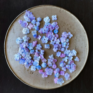 Artistic display of purple and blue embroidered flowers on a vintage tray.